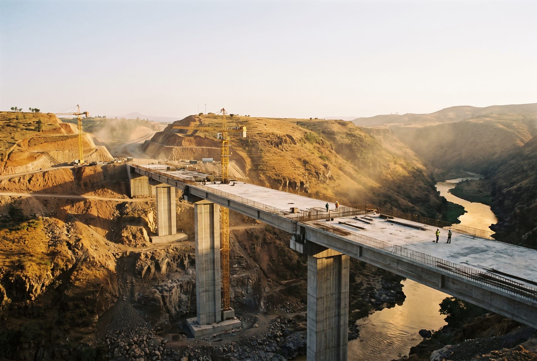 A road bridge under construction over a highland river gorge in Ethiopia with tall piers and a partly cast deck